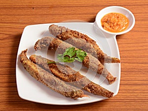 Fried Bombay duck fish or bombil in a plate with Lemon and coriander, famous food of Mumbai and coastal area of maharashtra, India