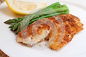 Fried breaded fish with asparagus and lemon