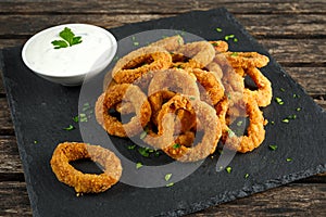 Fried Breaded Onion Rings with sauce on stone board