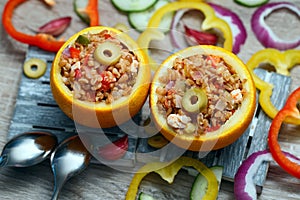 Fried bulgur with poultry meat and stewed vegetables served in cups made of orange peel. Exotic dish, top view