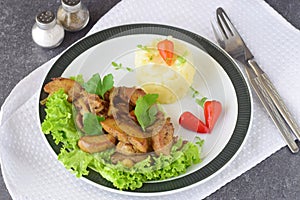 Fried bull testicles with cream and herbs served with mashed potato on a white plate on an abstract background. Healthy