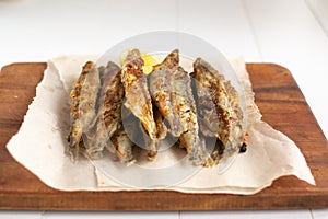 Fried capelin with lemon on baking paper on a white backgroun