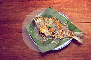 Fried carp fish freshwater is placed on dish and green banana leaf background
