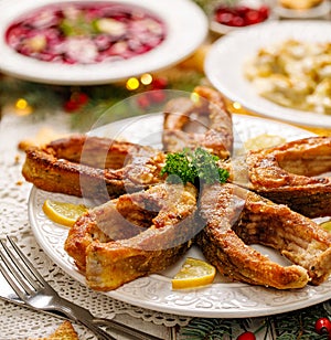 Fried carp fish slices on a white plate, close up. Traditional christmas eve dish.