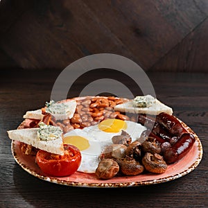 Fried champignons, fried eggs, juicy sausages, fried bacon, toast with butter and pickled beans in tomato sauce