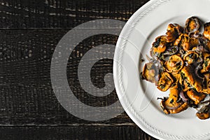 Fried chanterelles in the ceramic plate at the right of the old wooden table top view