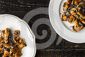 Fried chanterelles in the ceramic plates on the old wooden table top view