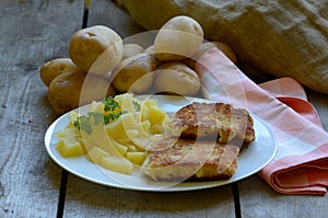 Fried cheese with homegrown peeled potatoes on wooden background