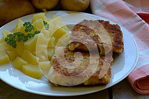 Fried cheese with homegrown peeled potatoes on wooden background