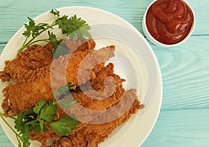 Fried chicken in breading, parsley, ketchup on blue wooden