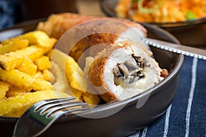 Fried chicken breast stuffed with mushrooms and cheese wrapped in ham served with fries and salad