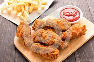 Fried chicken drumstick and french fries on wooden table