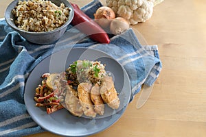 Fried chicken filet with cauliflower rice and vegetable ragout from bell pepper and mushroom, healthy diet meal blue plate and