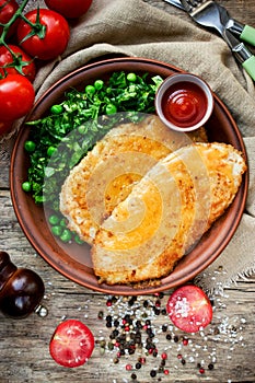 Fried chicken fillet with cheese crust and garnish of fresh vegetables