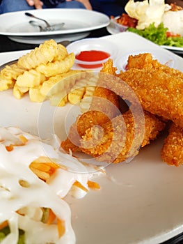 Fried chicken with french fries and salad on a white plate.