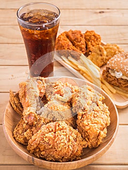 Fried chicken, french fries and soft drink on wooden table