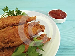 Fried chicken fried delicious in breading, parsley, ketchup on blue wooden
