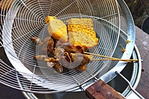 Fried chicken gizzard and liver satay with fried tofu and tempeh at food strainer