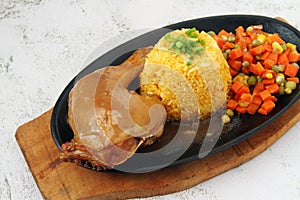 Fried chicken with gravy, fried rice and vegetables served on a hot plate