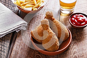 Fried chicken leg in breadcrumbs and french fries