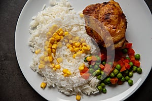 Fried chicken leg with rice, corn, carrots and peas