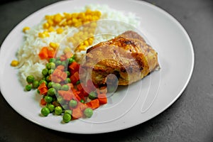 Fried chicken leg with rice, corn, carrots and peas