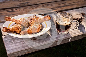 Fried chicken legs in a plate and a glass of beer/Fried chicken legs in a plate and a glass of beer on a wooden table. Picnic on a