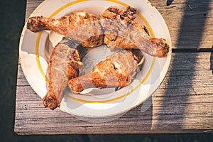 Fried chicken legs in a plate on a wooden table/Fried chicken legs in a plate on a wooden table. Top view. Sanny day