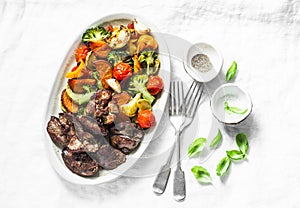 Fried chicken liver and baked seasonal vegetables - delicious healthy lunch on light background, top view