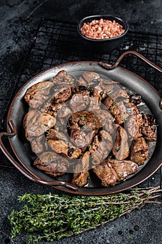 Fried chicken liver with onions and herbs. Black background. Top view photo