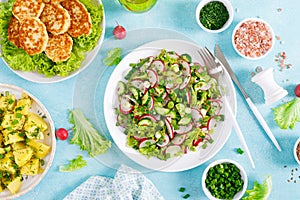 Fried chicken meat cutlets, fresh vegetable salad with radish, lettuce and cucumber, boiled new potato with butter, dill and green