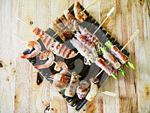 Fried chicken meat and seafood barbecue with vegetables on wooden skewers on a plate sauce. top view