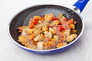 Fried chicken meat with sweet pepper in blue frying pan