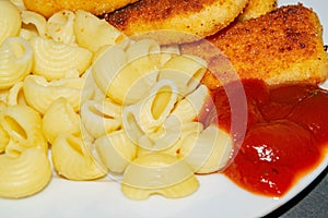 Fried chicken nuggets and boiled pasta with ketchup on a plate. Close up