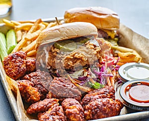 Fried chicken sandwich and cheeseburger in tray with fries and boneless wings