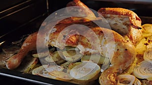 Fried chicken with spices and potatoes on a baking sheet is fried in the oven