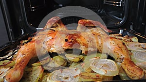 Fried chicken with spices and potatoes on a baking sheet is fried in the oven