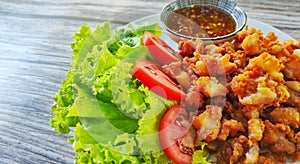 Fried chicken tendon served with sweet chilli sauce and green salad on white plate.