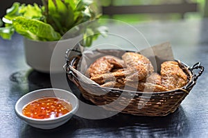 Fried chicken wings in basket, and sweet and sour sauce with chili for chicken dip