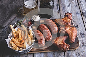 Fried chicken wings,grilled sausages, french fries, nuts, white and red sauce. food to beer