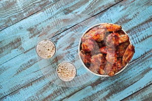 Fried chicken wings in paper bucket with lager beer