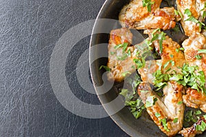 Fried chicken wings parsley on black pan and table.