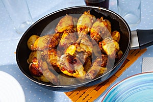 Fried chicken wings with potatoes served in fry pan