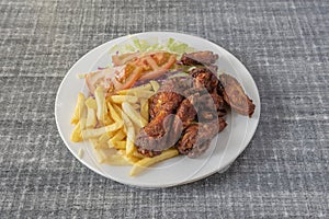 Fried chicken wings with salad and tomato and french fries served