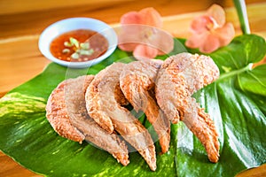 Fried chicken wings served on leaves with sauce top view - crispy chicken wings on wooden table , Thai Food Asian