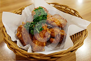 Fried chicken wings in white plate on wooden table.