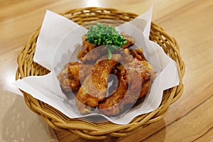 Fried chicken wings in white plate on wooden table.