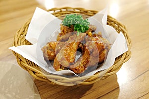 Fried chicken wings in white plate on wooden table.