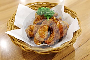 Fried chicken wings in white plate on wooden table.