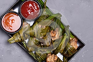 Fried chicken wrapped in pandan leaves in a black plate